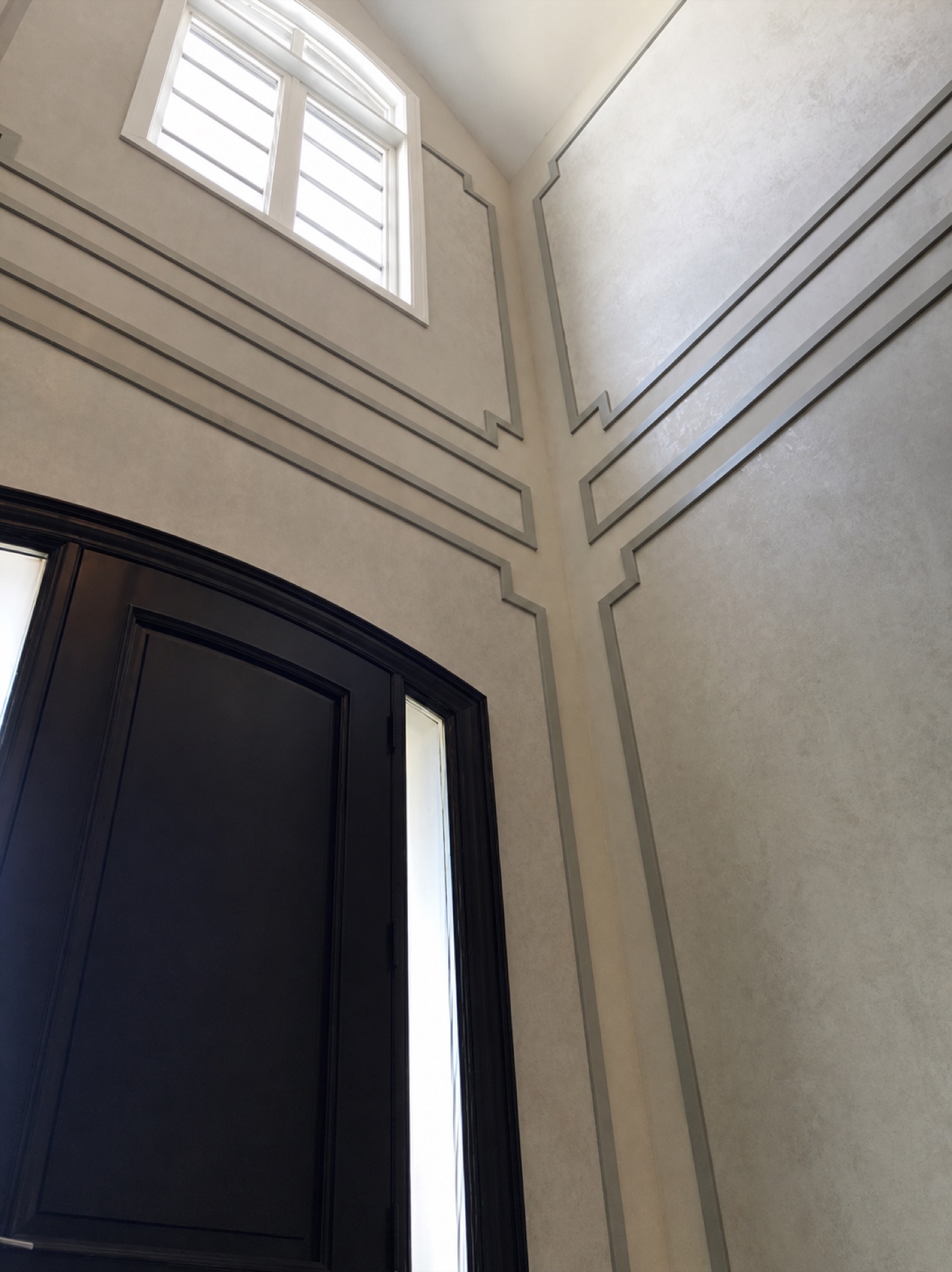 Two-storey foyer with applied wall moulding and a black door